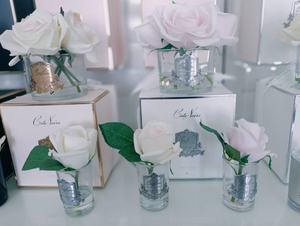 
                  
                    A display of many rosebuds in Natashas Skin Spa beauty salon on Southbank in Melbourne, on City Road. White boxes with silver crests and on top of them resting clear glass vases with silver and gold crests, filled with real touch roses in pink, ivory and blush tones.
                  
                